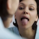 Woman examining tongue
